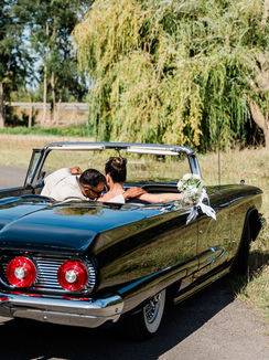 Mariés dans une voiture décapotable en extérieur.