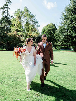 le frere de la mariee l'aide a marcher dans un parc, robe de mariée fluide, photo de mariage naturelle et lumineuse