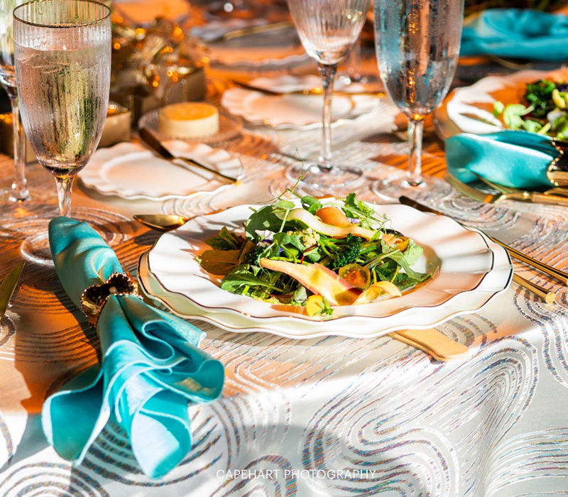 Elegant reception table place setting featuring a fresh salad, scalloped dinnerware, fine stemware, and teal napkins.
Photo credit: Capehart Photography