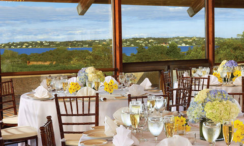 Elegant indoor reception with white table settings and hydrangea centerpieces, overlooking scenic waterfront views.