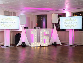 Event DJ setup with "Kaylee's Sweet 16" TV monitors flanking a large illuminated "16" sign.