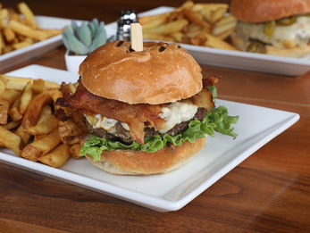 A gourmet bacon cheeseburger with lettuce served alongside a pile of french fries.