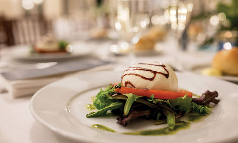 A close-up of a burrata and tomato appetizer with balsamic glaze.