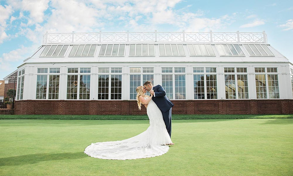 Bride and groom standing close on a brick patio with a golf course and greenery in the background.