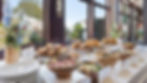 Buffet with sandwiches, salads, and floral arrangements, overlooking a patio.