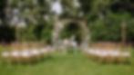 Outdoor wedding ceremony setup with floral arch and chairs.