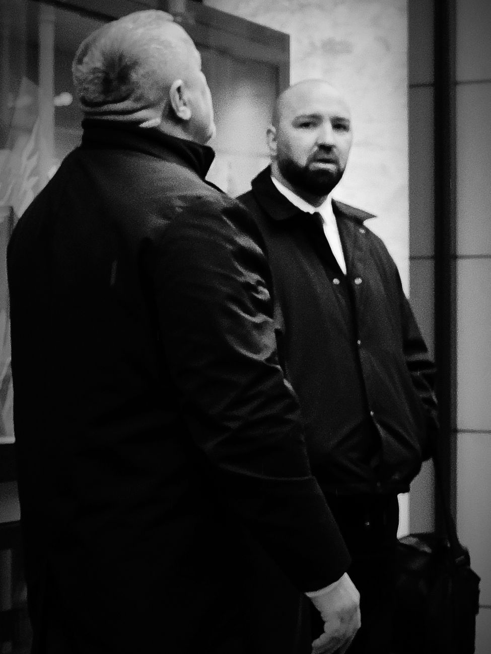 Two men talking indoors in black and white