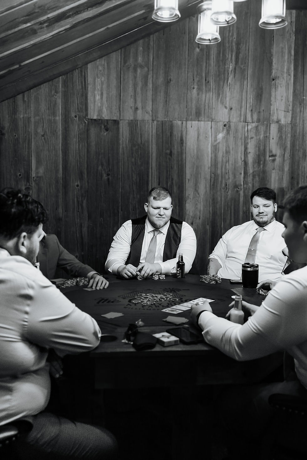 Barn Wedding Venues in Ohio. Men in shirts and ties play poker around a table in a wood-paneled room, with cards, chips, and drinks visible, creating a tense mood.