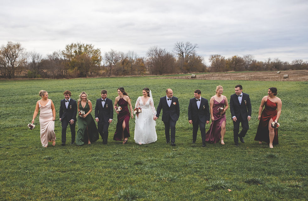 Barn Wedding Venues in Ohio. Wedding party walks through country field with haybales and trees in background.