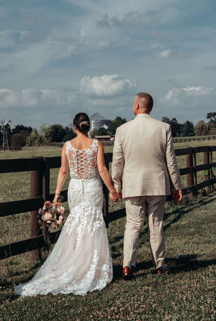 Bride and groom walking along fence line at peaceful full weekend wedding venue in Columbus Ohio