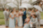 Ideas for Memorable Wedding Experience Ohio. Wedding party in light blue and gray outfits holds clear umbrellas outdoors. Joyful mood with greenery in the background. Flowers visible.