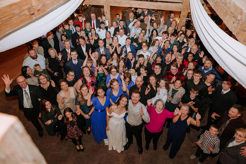 Grove City, OH Wedding Venue Large wedding crowd in a rustic hall smiles and waves up at the camera under white drapes and wooden beams.