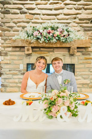 Bride and groom at sweetheart table in front of fireplace at Ohio barn wedding venue with lodging