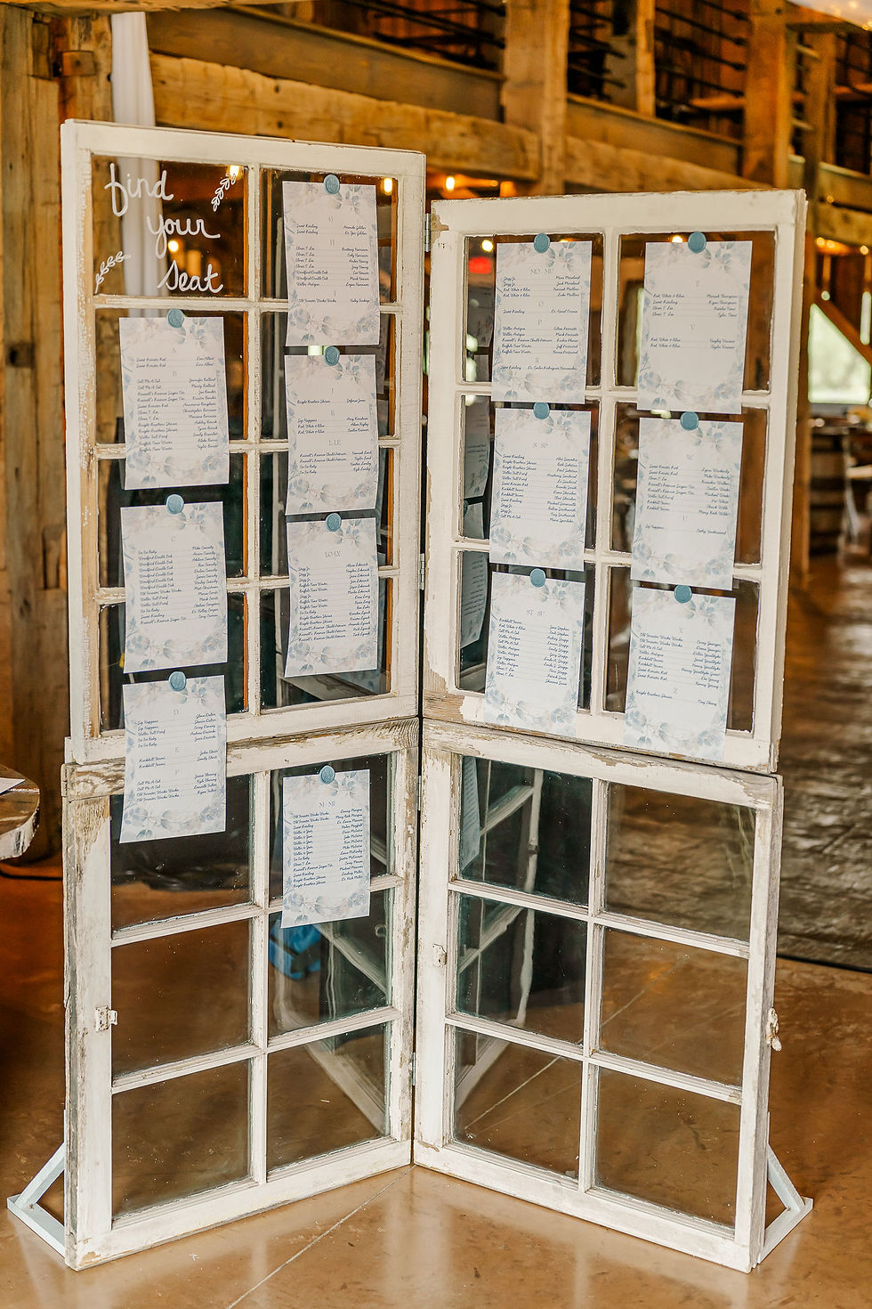 Pickaway County Wedding Venue Rustic white window frame wedding seating chart with floral cards and find your seat text in a warm barn setting