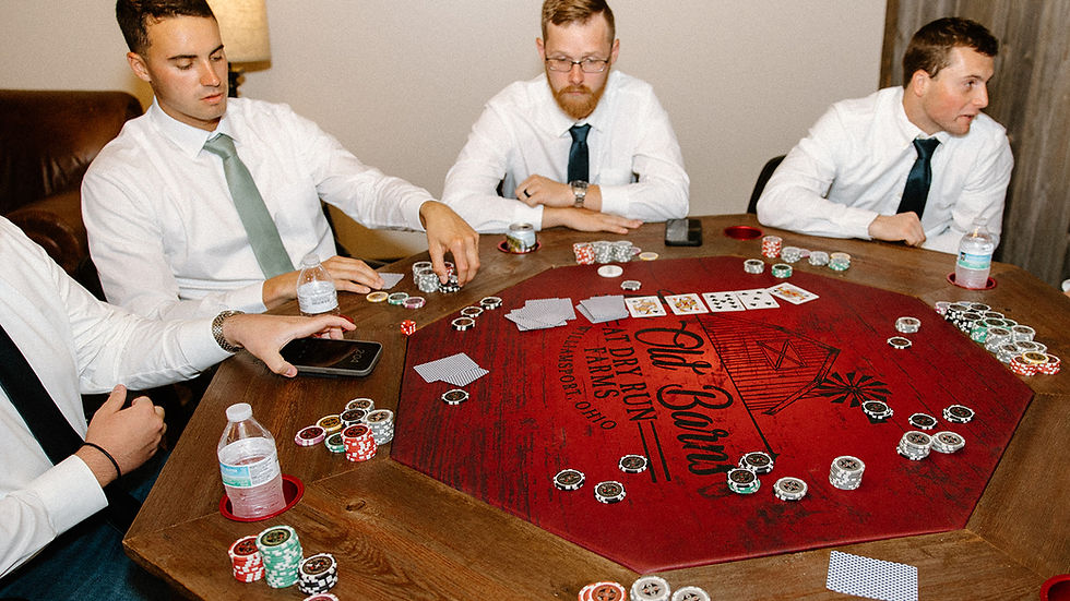 wedding venue Ohio Four men in white shirts play poker at a red octagonal table. Poker chips and cards are scattered. The atmosphere is focused.