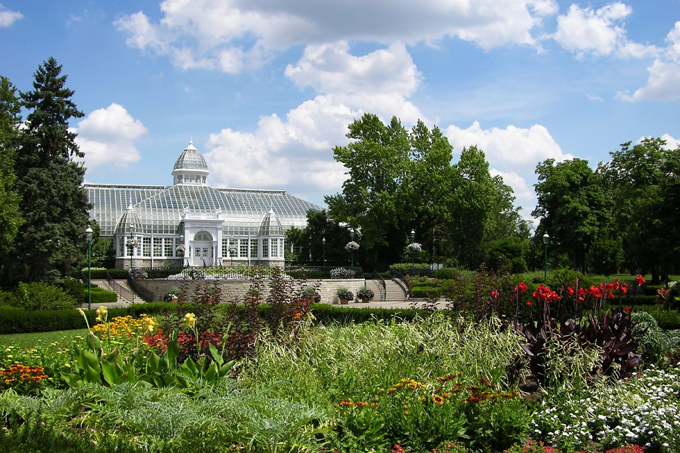 columbus wedding venues A glass conservatory amidst lush gardens with vibrant flowers. Blue sky with fluffy clouds in the background. Peaceful atmosphere.