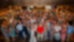 Barn Wedding Venue Ohio. A large group poses at a barn wedding. The bride and groom stand at the front, surrounded by guests in colorful attire, creating a joyful scene.