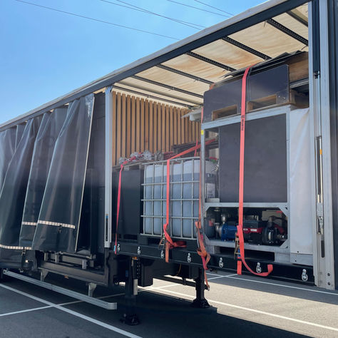 Logistics truck parked beside white tents with equipment and materials prepared for event setup.