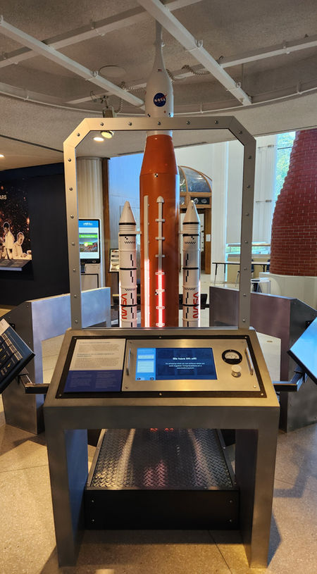 A rocket behind a window with a kiosk in front