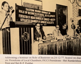 Sepia photo: Ajay Rungta at a podium, addressing a FICCI seminar in 1977. A banner on rural development is visible behind him.
