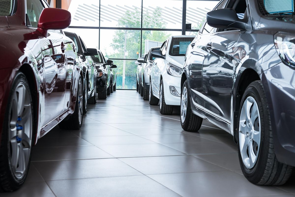 Cars in a showroom, lined up on a tiled floor. The vehicles are red, black, and white, with large windows in the background.