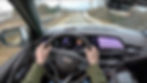 POV driving a Cadillac with dashboard showing 55 mph, navigation displaying a map. Road ahead is clear, scenery includes trees and snow.
