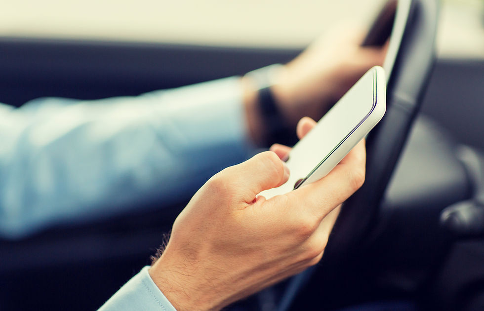 A person in a blue shirt holds a smartphone, texting while steering a car. The image conveys multitasking and potential distraction.