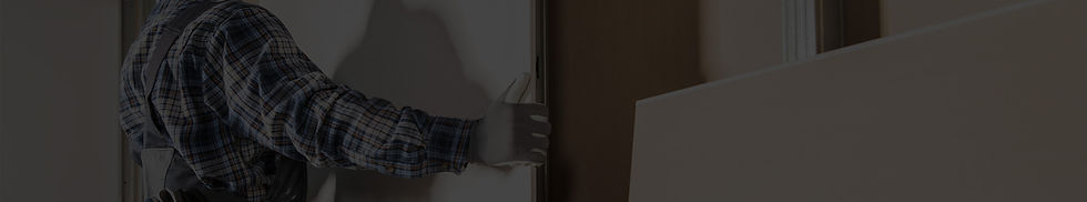 A worker carrying a drywall sheet, ready for installation to create a smooth and durable surface.