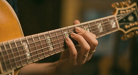Gros plan sur les mains d'un guitariste jouant un accord sur le manche d'une guitare pour l'agence Impulsion