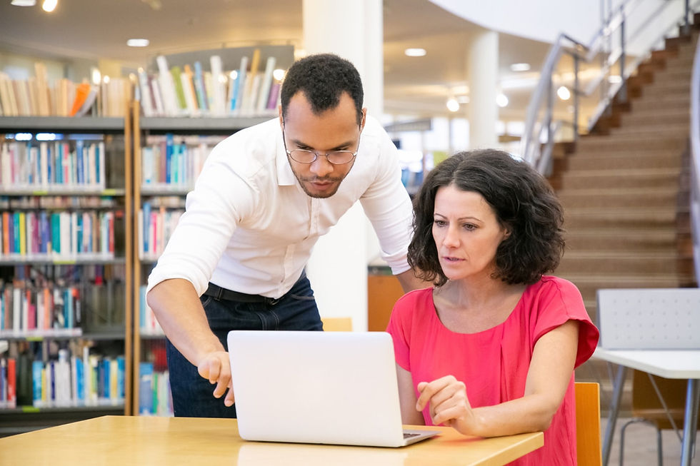 A younger, more hip teacher explains technology to an older confused teacher.