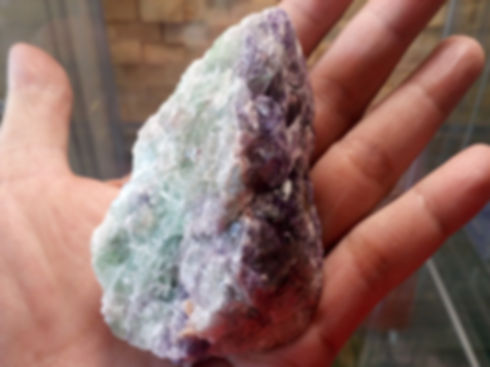 Hand holding a green and purple fluorite crystal