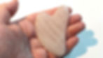A hand holding a rose quartz crystal Gua sha massage tool