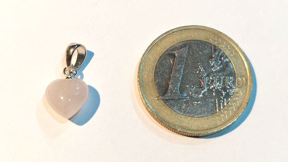 A Rose Quartz Crystal Heart Pendant with a Sterling Silver Bail next to a one Euro coin