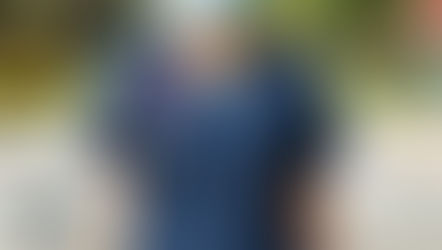     A healthcare professional wearing blue scrubs and a mask stands at a crossroad.