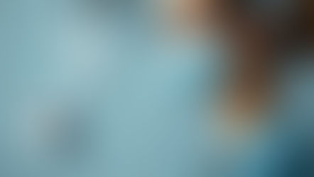 A nurse in scrubs and a face mask stands thoughtfully in a hospital setting, symbolizing dedication and focus in the medical field.