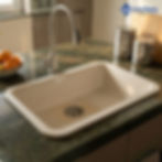 White quartz kitchen sink installed with pull-down faucet on polished stone countertop, bright and modern kitchen setup.
