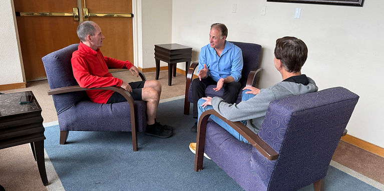 Klaus talking to two seated men in a mens mastermind