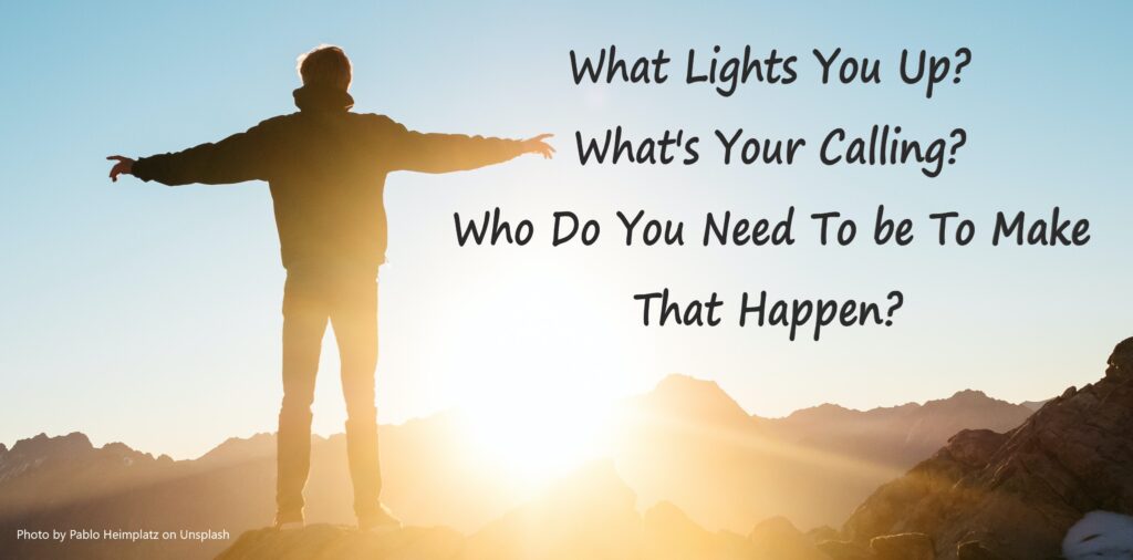 Man standing on a mountain looking out at sunrise with arms spread.