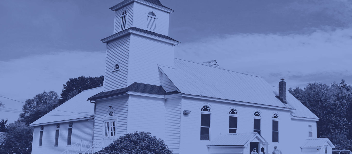 Trinity Lutheran Church building with cross on top and people standing at the entrance.