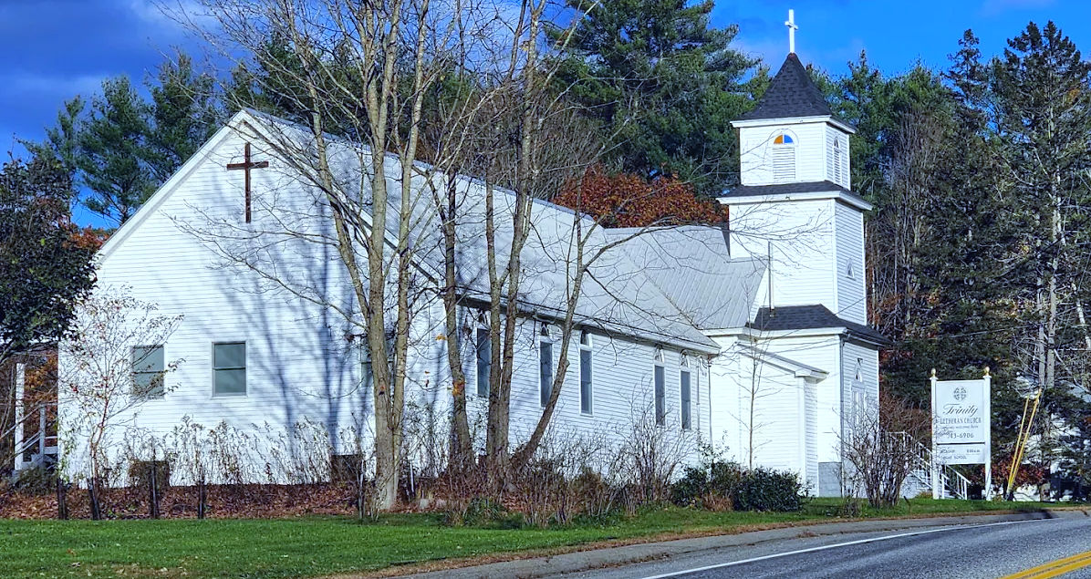 Trinity Lutheran Church building with cross on a sunny day near road.