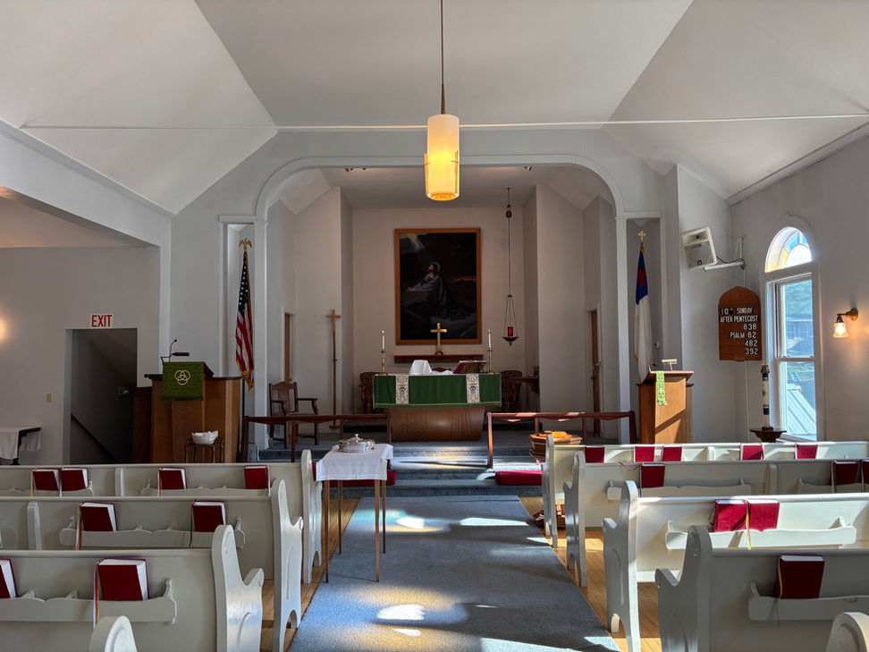 Interior view of a church with rows of pews and an altar visible.