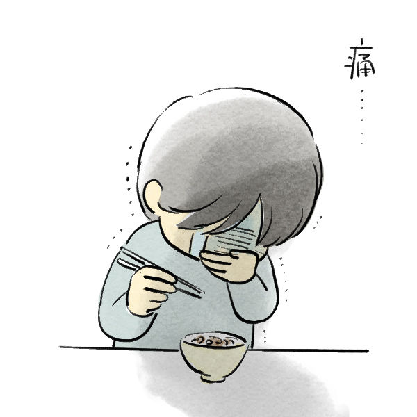 食べ物が沁みて痛がっている食事中の人物