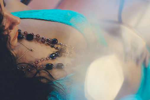 Dreamlike boudoir portrait of a woman in turquoise lingerie photographed through a soft lens flare