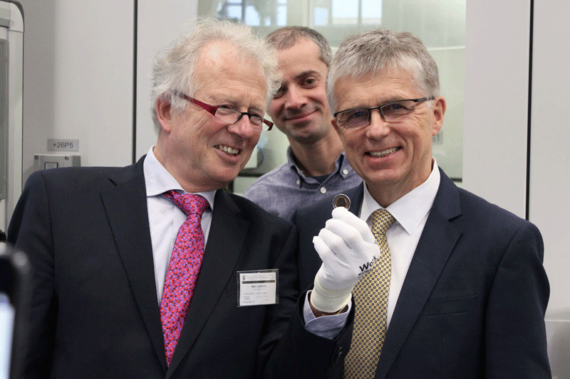 Ministerialdirigent Walter Leibold (links), Künstler Patrick Niesel, Münzleiter Dr. Peter Huber. Münzrohling mit orangefarbenem Polymerring.