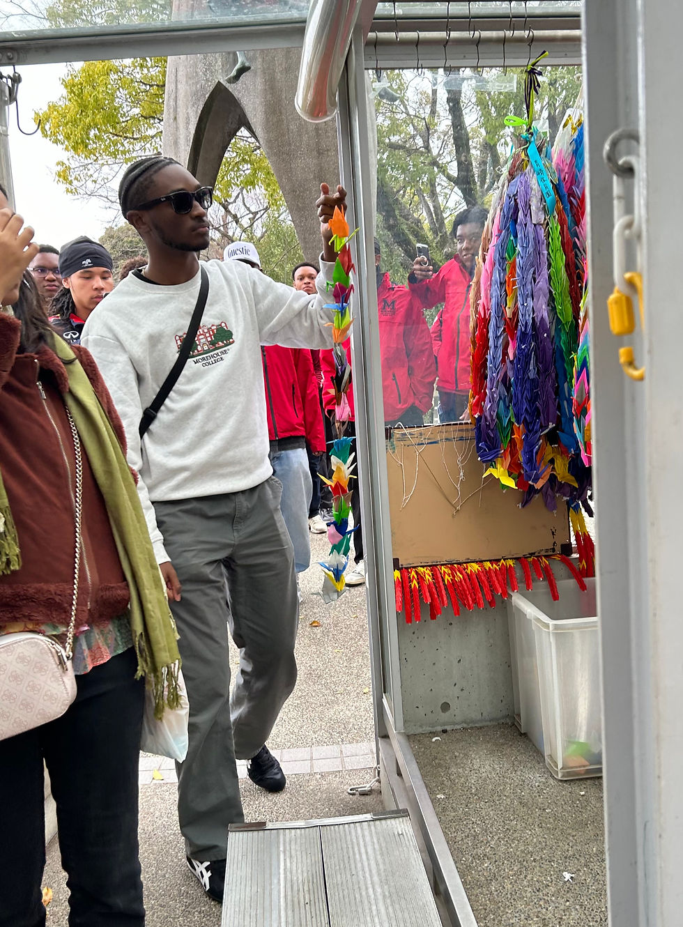 Rollin Jackson '2025 hanging our origami cranes. It has become a tradition to hand origami cranes near the Hiroshima Peace Memorial Museum. The cranes are a representation of peace, hope, and healing.