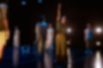people stand around the space, one raises their hand to the sky