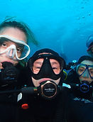 Groep van vier duikers in duikuitrusting die onderwaterselfi maken met duikmaskers en ademautomaten in helder blauw water