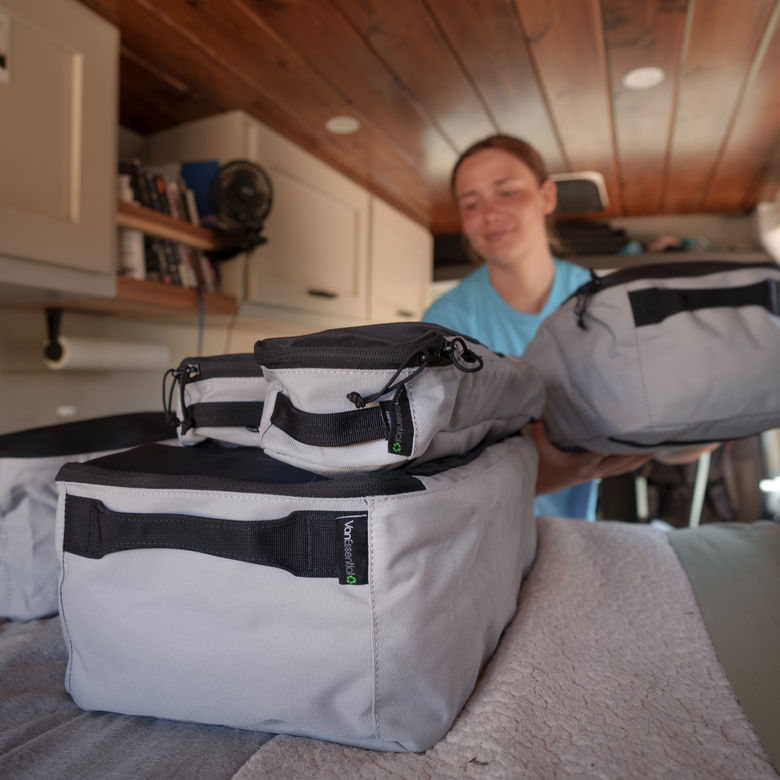 Person organizing grey VanEssential storage cubes in van
