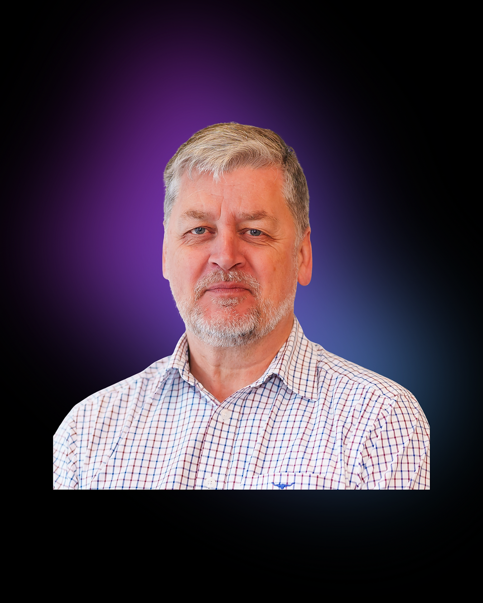 Man with gray hair and beard in checked shirt against a gradient purple and blue background, neutral expression, no visible text.