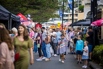 Attendees walking through the street of a festival lined with market stalls
